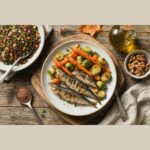 Assiette de sardines grillées avec choux de Bruxelles, carottes rôties, salade de lentilles et cerneaux de noix sur table en bois.